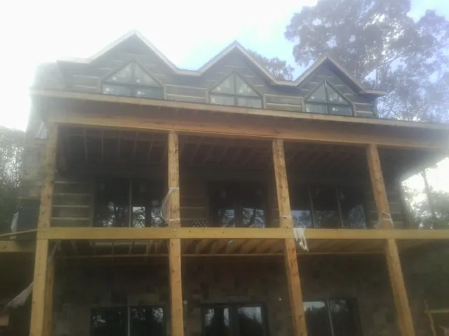Dormers and porch framing on a large log home under construction — Roof Coating work by our crew in Mc Rae Helena
