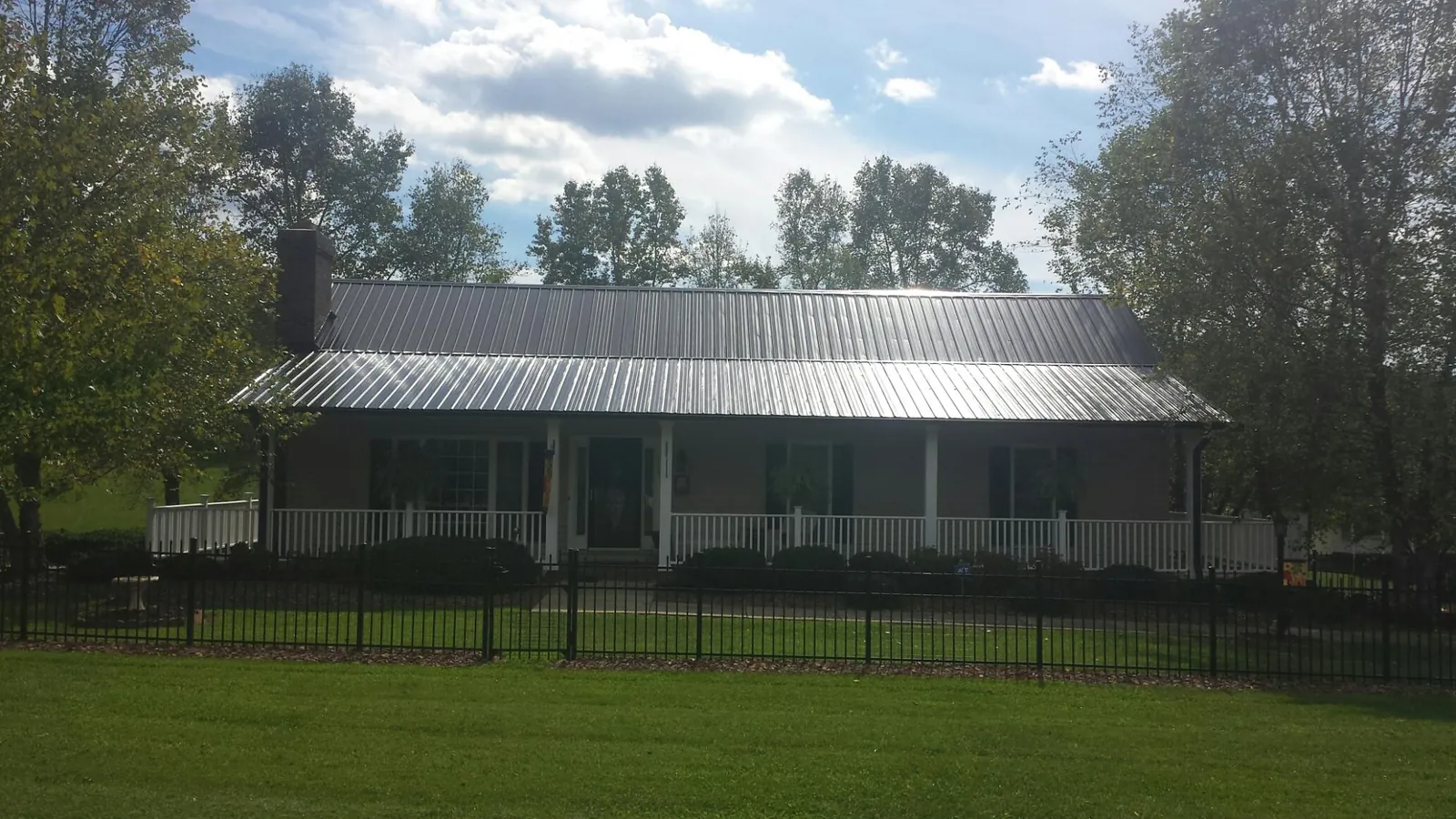 Gray metal roof on a brick ranch with a full width front porch — Gutter Guard Installation work by our crew in Mc Rae Helena