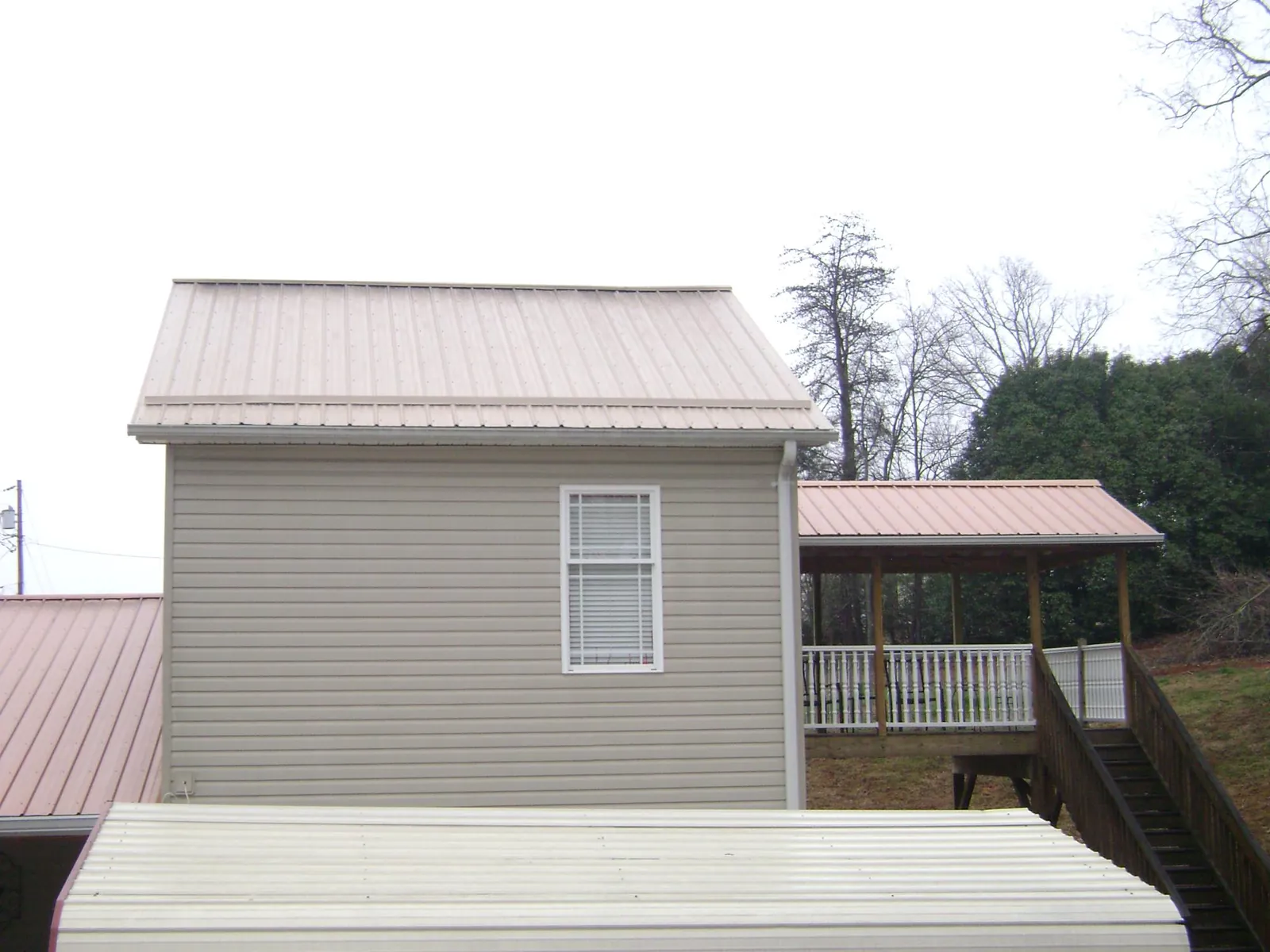 Tan metal roofs on a two story addition and attached porch, from a Roof Replacement job in Mc Rae Helena