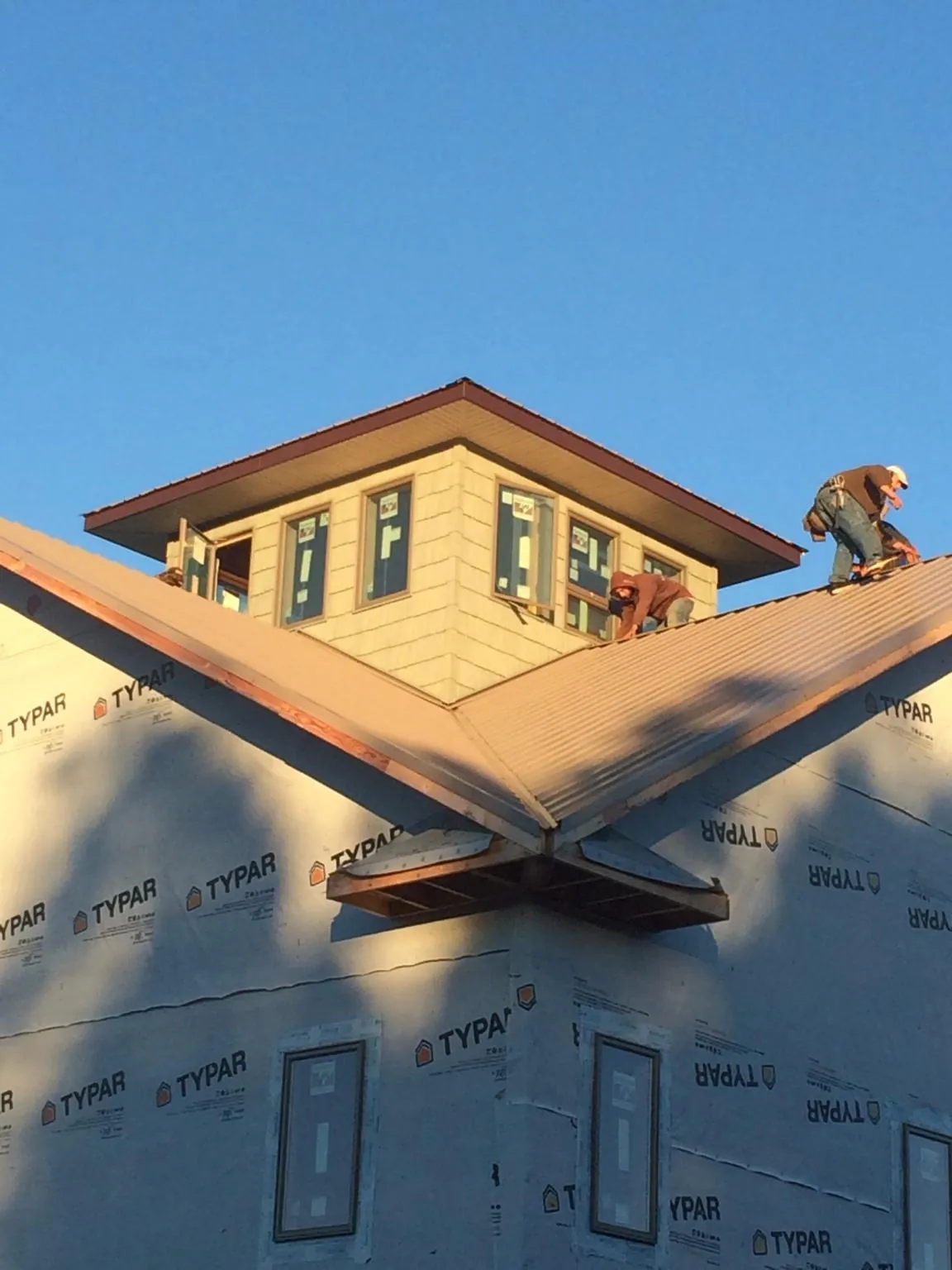 Roofers working around a rooftop cupola on a new metal roof at sunset — Roof Waterproofing in Mc Rae Helena by Roofing Brothers
